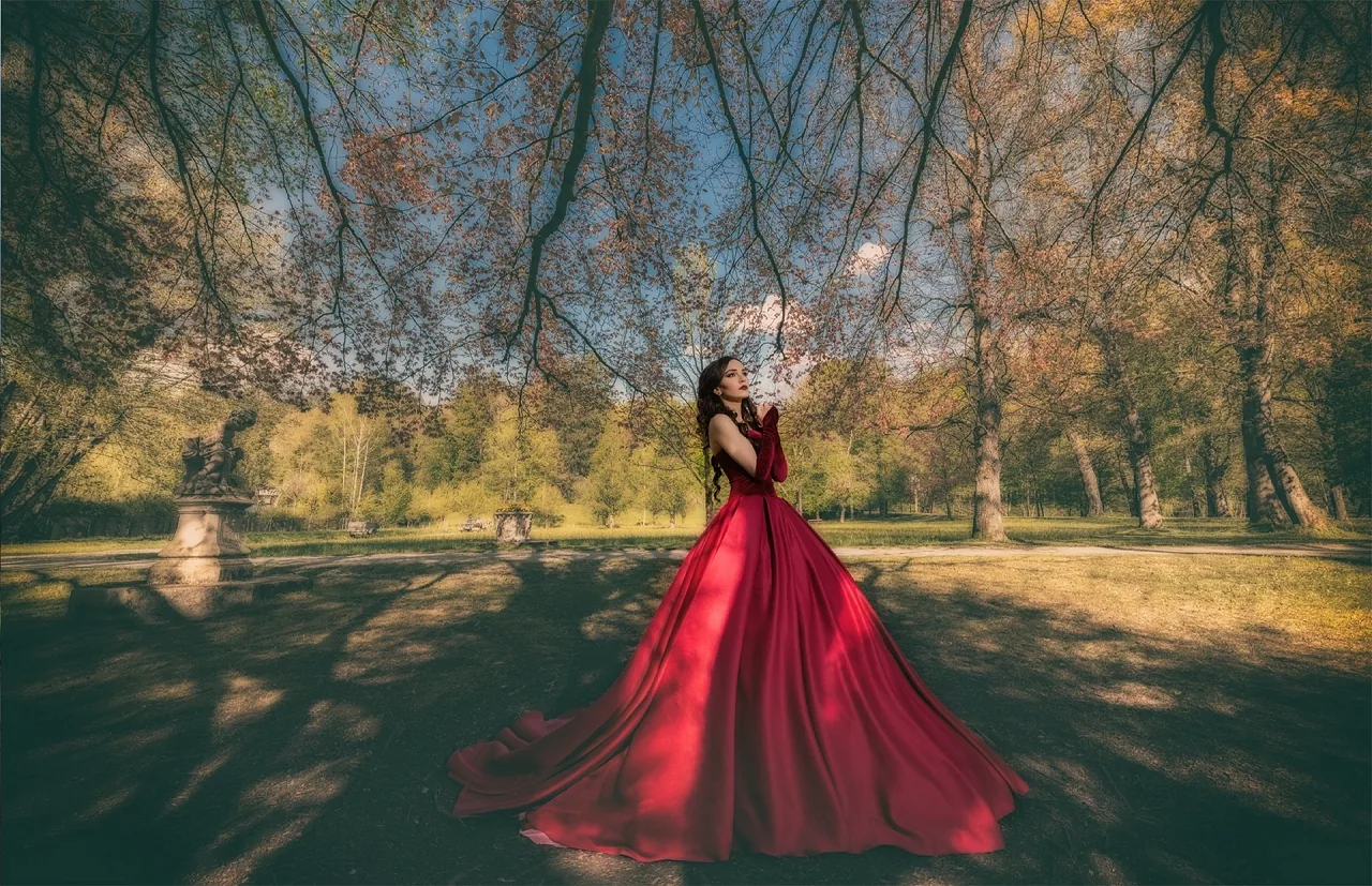 Braut in rotem Kleid in einer Parklandschaft